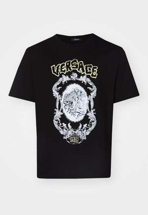Must musta T-särk, millel on detailne valge graafiline disain keskel oleva medaliiniga, mille ülal on tekst "VERSACE" ja all "1978".
