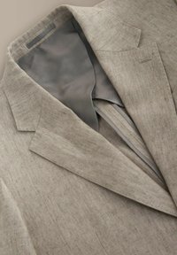 Világosbarna halszálkamintás blézer bemetszett nyakkal és szürke bélés belsővel, laposan kiterítve, gallér és elöl átfedés látható.