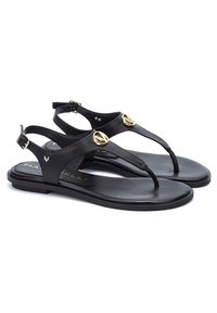 Sandales thong en cuir noir avec des accents circulaires dorés, bride de cheville et semelle plate. Texture lisse, design minimaliste et style ouvert.