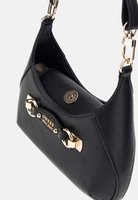 Bolso de mano de cuero sintético negro con forma curvada, acentos de hardware dorado y una placa con el logotipo. Presenta un diseño compacto con una única correa para el hombro.