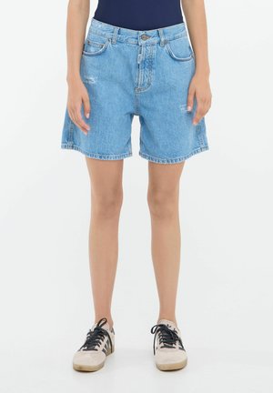 Shorts in denim azzurro chiaro con una vestibilità rilassata, caratterizzati da bordi sfilacciati, cinque tasche e passanti per cintura. Abbinati a sneakers color crema.