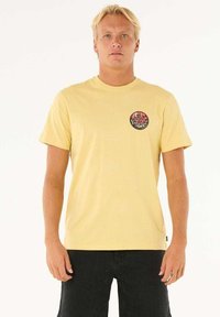 Geel katoenen t-shirt met een ronde halslijn, korte mouwen en een ronde grafische print in rood en zwart op de linkerborst.