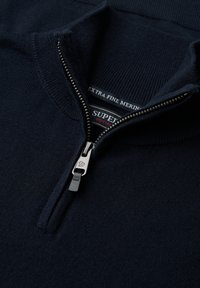 Marine merinowollen pullover met een ritskraag. Heeft een geribde kraag en manchetten, en een zichtbaar merkje binnenin de kraag.