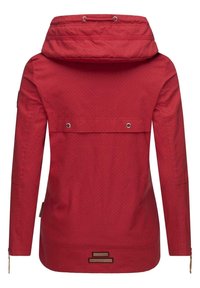 Chaqueta impermeable roja con capucha, que presenta un patrón de lunares, un bolsillo delantero con tapa y ojales de metal. Incluye dos bolsillos laterales con cremallera.