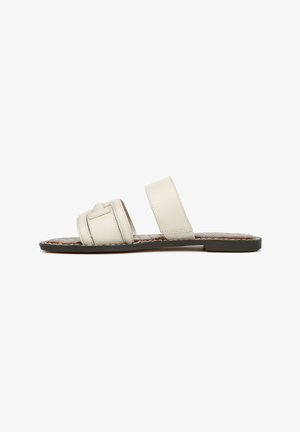 Light beige slide sandals with two wide straps and braided detailing on a brown textured insole, featuring a flat black sole.