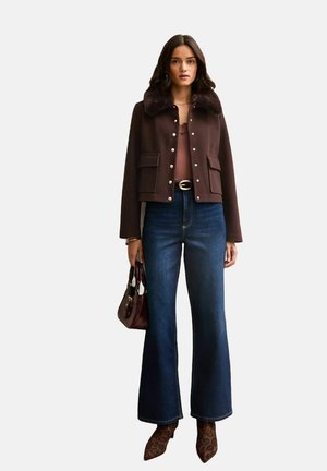 Bruine cropped jas met nepbontkraag, gecombineerd met een top met lage ronde hals, hooggetailleerde wijde jeans en schoenen met luipaardprint. Bordeauxrode handtas.