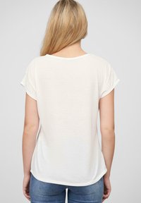 Biele tričko s krátkym rukávom a okrúhlym výstrihom, s oblým lemom, vyrobené z ľahkej tkaniny, zobrazené zozadu na jednoduchom pozadí.
