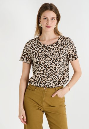 Camiseta de algodón con estampado de leopardo, cuello redondo y mangas cortas, combinada con pantalones verde oliva. Textura suave, corte casual.