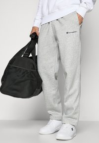 Grijze katoenen joggingsbroeken met een elastische tailleband, met zijzakken en een klein marineblauw logo. Draag ze met witte sneakers en een zwarte sporttas.