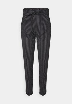 Pantalons rayés noir et blanc avec une taille élastique et un cordon de serrage, dotés de poches latérales et d'une coupe fuselée.