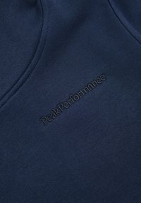 Marineblaues Sweatshirt mit glatter Textur, das in der Mitte ein geprägtes "PeakPerformance"-Logo trägt. Einfaches, minimalistisches Design.