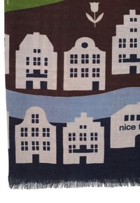 Pletený šál s opakujúcim sa vzorom stylizovaných domčekov v krémovej a hnedej farbe, s modrými akcentmi a čiernymi detailmi, ukončený třásňami.