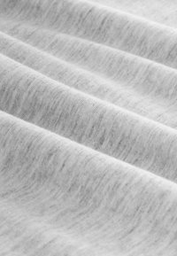 Tela gris claro con una textura suave, que presenta variaciones sutiles en color y patrón, doblada en ondas suaves.