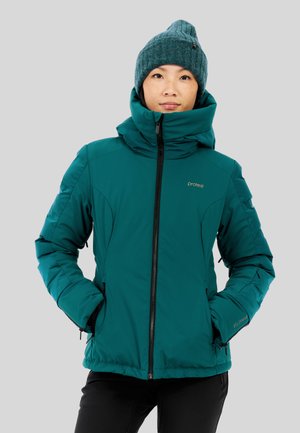 Teal geïsoleerde jas met hoge kraag en ritssluiting aan de voorkant. Zwarte rits en manchetten, voorzien van twee zijzakken. Gebreide teal beanie als accessoire.