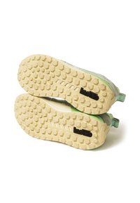 Sole di sneaker verdi e grigie con un motivo in gomma testurizzata; presenta un logo nero e un linguetta sul tallone.