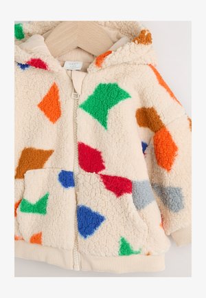 Krém színű polár kapucnis dzseki, piros, narancssárga, zöld, kék és barna színű, többszínű geometriai mintákkal. Cipzáras elülső rész és zsebek találhatók rajta.