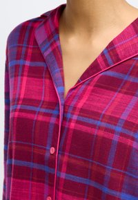 Geruite flanellen overhemd in roze en blauwe tinten, met een geknipt kraag en contrasterende roze piping, en roze knopen op de sluiting.