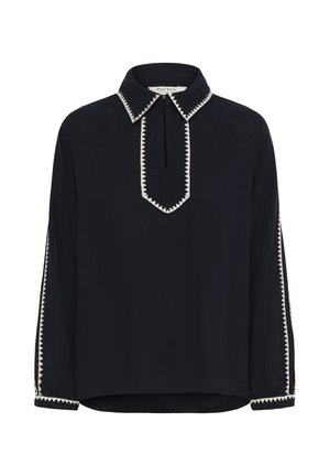 Blouse noire à manches longues avec bordure blanche en zigzag sur le col, la patte de boutonnage, les poignets et des rayures sur les manches, ornée d'un petit bouton au niveau du cou.