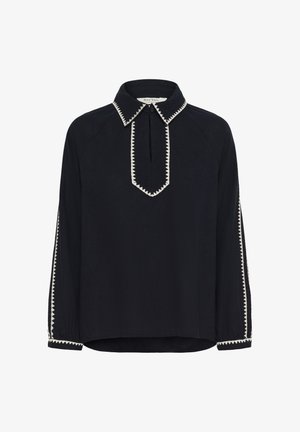 Mustast pikkade varrukatega pluus, millel on zigzag-valge ääris krae, eesosaõmblus, mansetid ja varruka triibud ning väike nööp kaelusel.