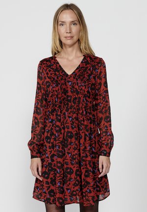 Robe floral rouge à manches longues, décolleté en V, texture froncée, avec des motifs de fleurs noires et bleues sur un tissu transparent.