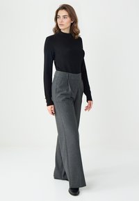 Zwarte langemouwen top gecombineerd met hooggewaisted, wijdvallende grijze broeken met een subtiel patroon, een nette pasvorm en een soepele textuur.