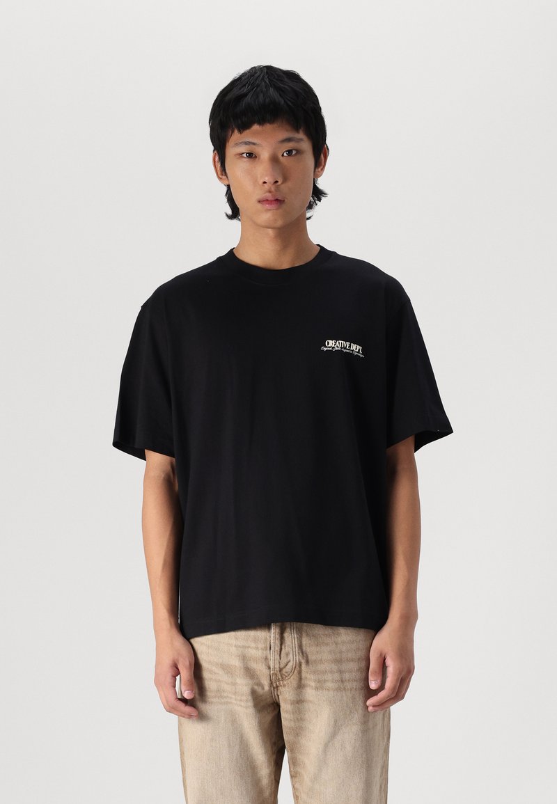 Sort bomulds T-shirt med løs pasform, rund halsudskæring og korte ærmer. Har hvidt varemærke logo på venstre brystområde.