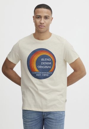Beige bomulds T-shirt med et cirkulært grafik i blå, orange og rød. Teksten inkluderer "BLEND DENIM ORIGINAL" og "EST. 1993."