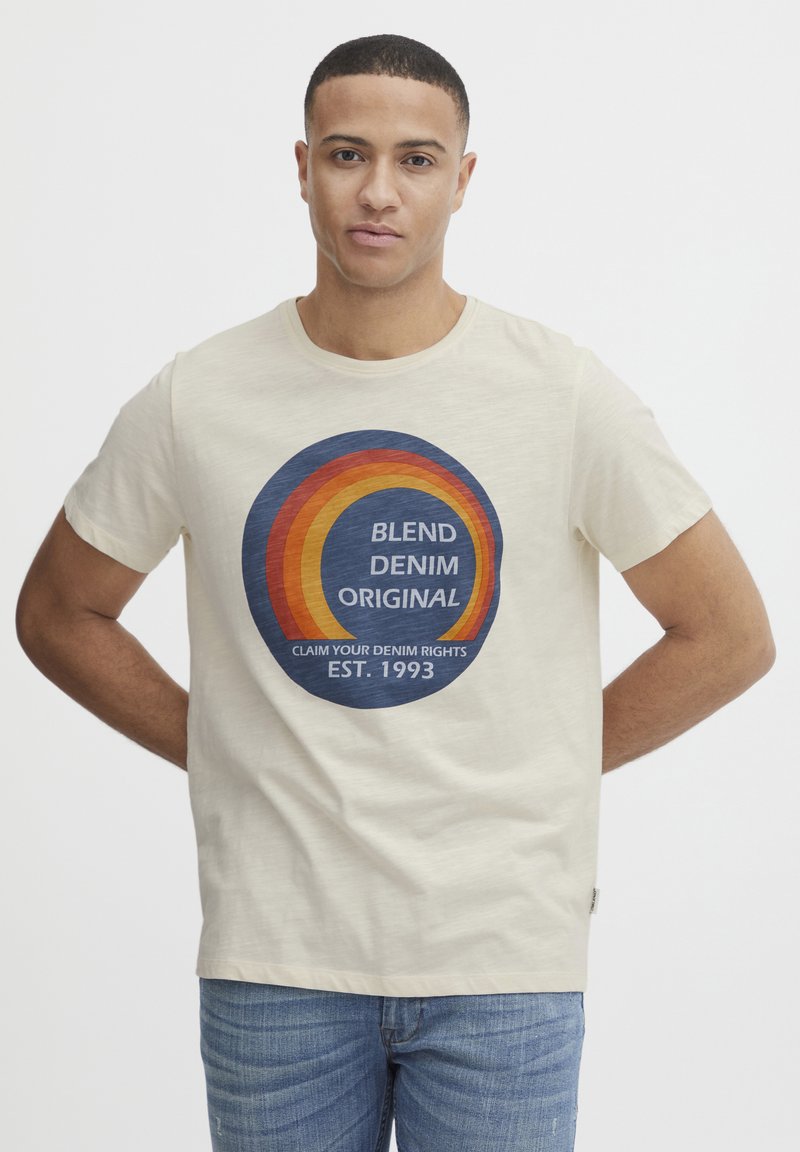 Camiseta de algodón beige con un gráfico circular en azul, naranja y rojo. El texto incluye "BLEND DENIM ORIGINAL" y "EST. 1993."