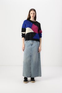 Strickpullover mit geometrischen Mustern in Blau, Pink, Weiß und Schwarz, kombiniert mit einem langen Jeansrock und schwarzen Sneakern.