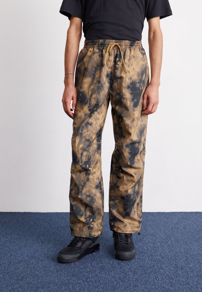 Tryckta sweatpants i en brun och svart tie-dye-mönster, med elastisk midja och snörning samt sidofickor.