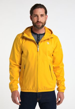 Jachetă galbenă cu fermoar și glugă, cu manșete elastice, având două buzunare laterale și un logo pe piept, purtată peste o cămașă în dungi.