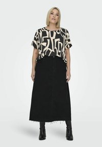 Black denim maxi skirt with frayed hem, paired with a beige and black abstract patterned blouse, featuring short sleeves and a relaxed fit.