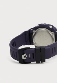 Bracelet de montre en silicone violet avec des accents noirs, doté d'un fond de boîtier métallique et d'un motif texturé sur le bracelet pour une meilleure prise.