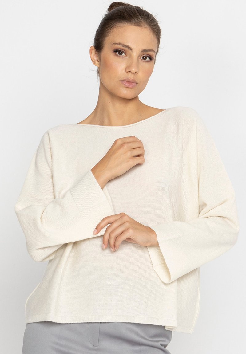 Lekki, kremowy sweter z dekoltem w łódkę, luźnym kroju, szerokimi rękawami i prążkowaną fakturą. Prosty design bez wzorów.