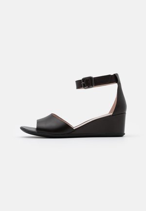 Sandale compensée en cuir noir avec bout ouvert et bride de cheville réglable avec boucle carrée en métal.