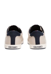 Beiga canvas sneakers med marinblå accenter och en vit gummisula. Har en platt häl, rund tå och logotypdetalj på hälen.