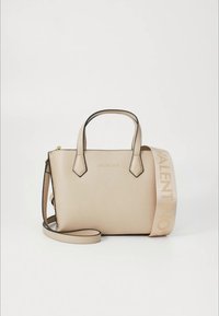 Beigen värinen nahkainen käsilaukku, jossa on kaksi yläkahvaa ja säädettävä olkahihna. Sillä on sileä pinta ja etuosassa kohokuvioitu logo.