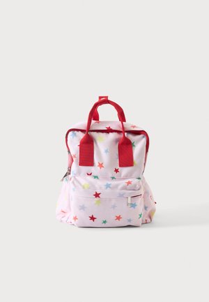 Petit sac à dos rose avec des poignées rouges et des motifs d'étoiles multicolores, poche avant zippée, isolé sur fond gris clair.