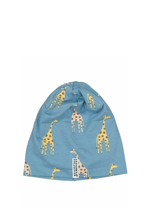 Ljusblå mjuk tygmössa med mönster av gula och beige giraffer och en liten vit "Geggamoja Collection"-etikett.
