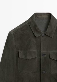 Giacca in suede verde scuro con colletto, chiusura frontale con bottoni e due tasche sul petto con patta su sfondo bianco.