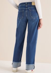 Blaue Jeans aus Denim mit geradem Bein und umgeschlagenen Säumen. Verfügt über ein Etikett am hinteren Bund und zwei Gesäßtaschen. Glatte Stoffstruktur.