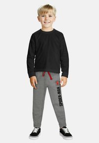 Black long-sleeve shirt and gray sweatpants with red drawstring, featuring a Spider-Man graphic and black text along the side. Black sneakers.
