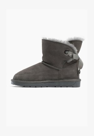 Harmaa mokkanahkasaapas nilkkamittaisella, jossa on tekoturkisvuori ja nauhakiinnitys. Varustettu litteällä kumipohjalla ja pyöristetulla kärjellä. Yhtenäinen sileä pinta.