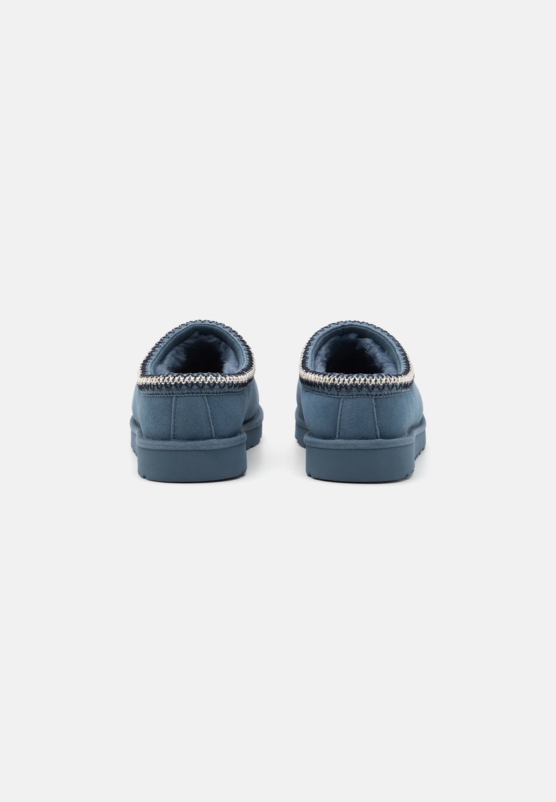 Chaussures à enfiler bleues avec un dessus en tissu doux, semelle texturée et un bord décoratif autour du col. Fini lisse avec une forme arrondie.
