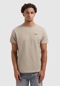 Beige katoenen t-shirt met een ronde hals en korte mouwen, met een klein zwart "Ballin" logo op de linkerkant van de borst.