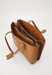 Sac fourre-tout en cuir marron avec deux compartiments, fermeture éclair dorée et éléments décoratifs en métal. Dispose de longues poignées et d'une base plate pour une meilleure stabilité.