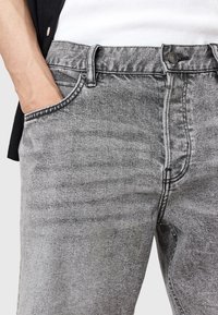 Grå denimjeans med en subtil textur, femficksdesign, kontrasterande vit sömnad och midjehögt gummiband.