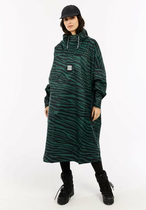 Groene en zwarte gestreepte regenjas met hoge kraag, trekkoord en voorzak; gecombineerd met zwarte broek en kniehoge laarzen.