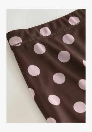 Brunt stof med prikker og store lyserøde cirkler. Materialet ser let og struktureret ud, med synlige sømme langs kanten.