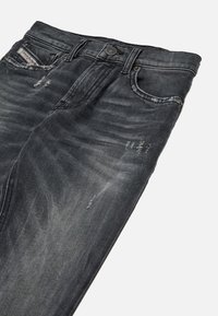 Tmavošedé džínsy z denimu s vyblednutým povrchom, so zničenými detailmi, dizajnom s piatimi vreckami a kovovým gombíkom na uzavretie v pase.